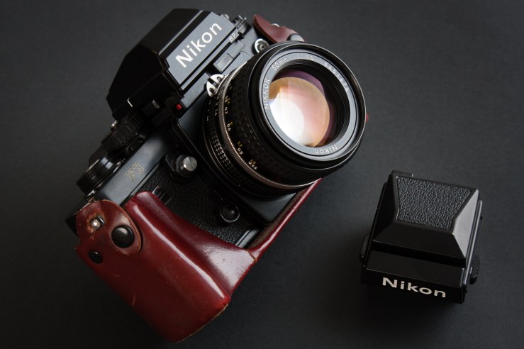 Nikon F3 in leather half case with Nikkor 50mm f/1,4 and HP prism. Waist level finder next to it.